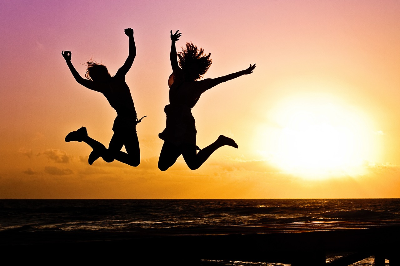 image showing 2 teens jumping silhouetted against bright orange setting sun